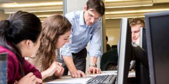 People looking at papers on a desk in front of computer