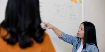 woman pointing at writing on a white board