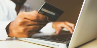 person holding credit card while typing on laptop